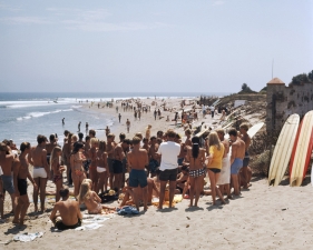 LeRoy Grannis<br /> <em>Watching a Beach Hair Cut, Malibu Surf Rider Beach,</em> 1967<br /> Chromogenic print<br /> 36 x 36"<br /> Edition of 18